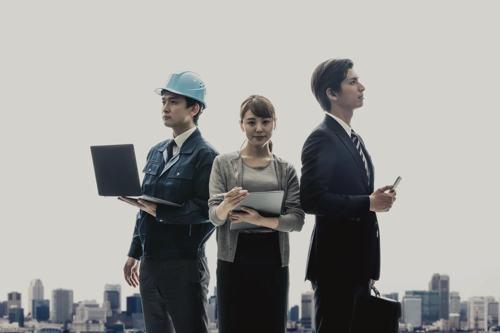 街を背に立つ3人の働く人
